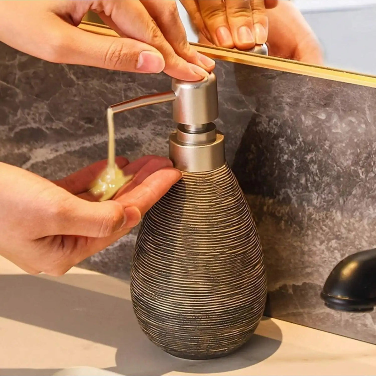 Person using a textured soap dispenser on a marble countertop