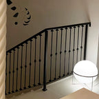 Black metal railing against a white wall with a modern floor lamp.