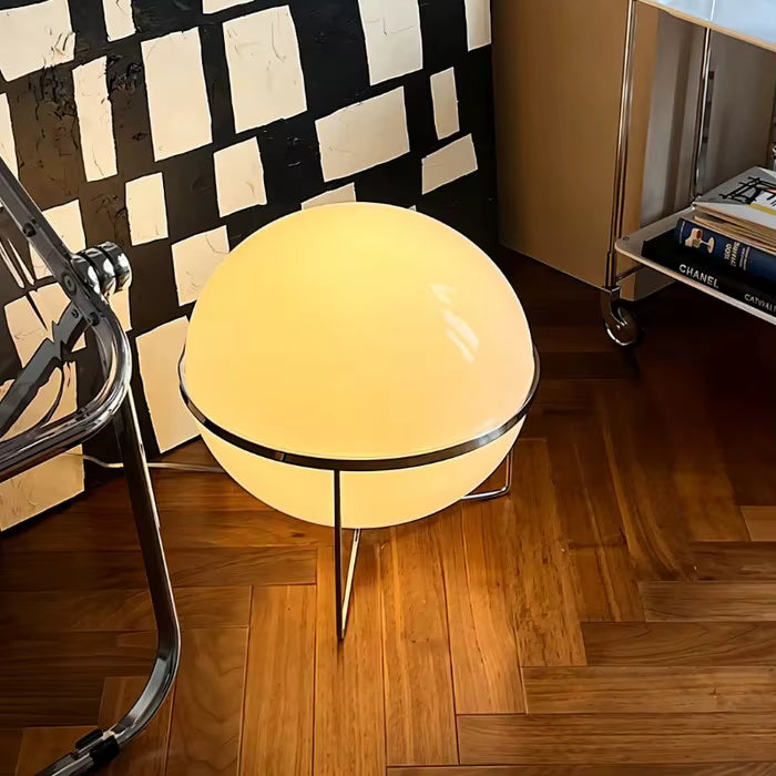 Round table with a glowing surface on a wooden floor, next to a checkered wall.