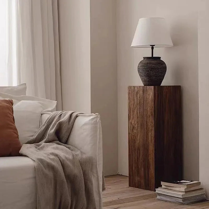 Napkin holder with decorative items on a wooden stand in a room setting.