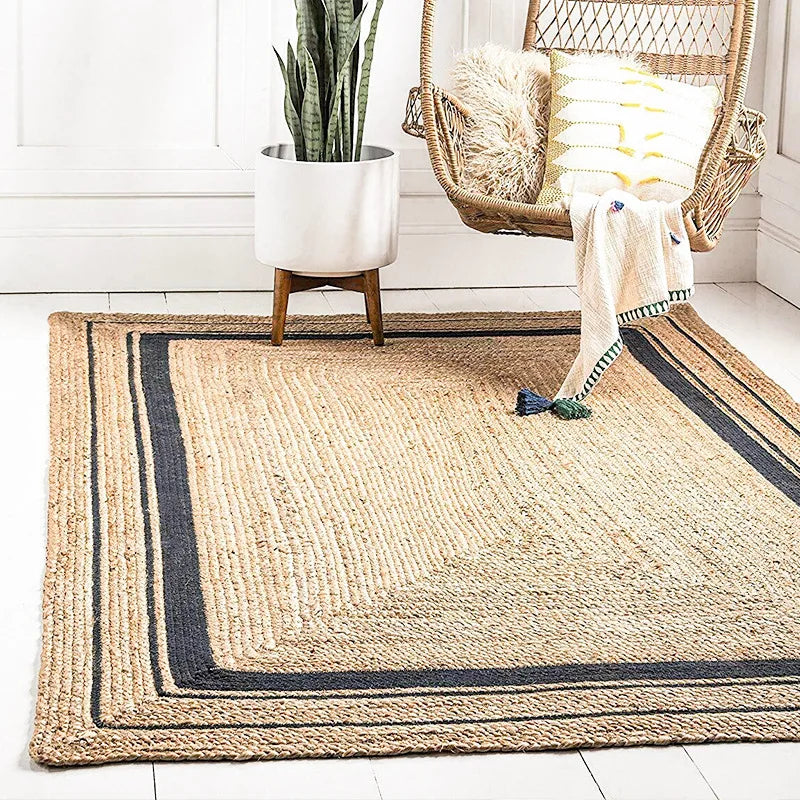 Jute rug with black border in a room with a chair, plant, and towel.