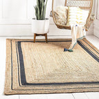 Jute rug with black border in a room with a chair, plant, and towel.