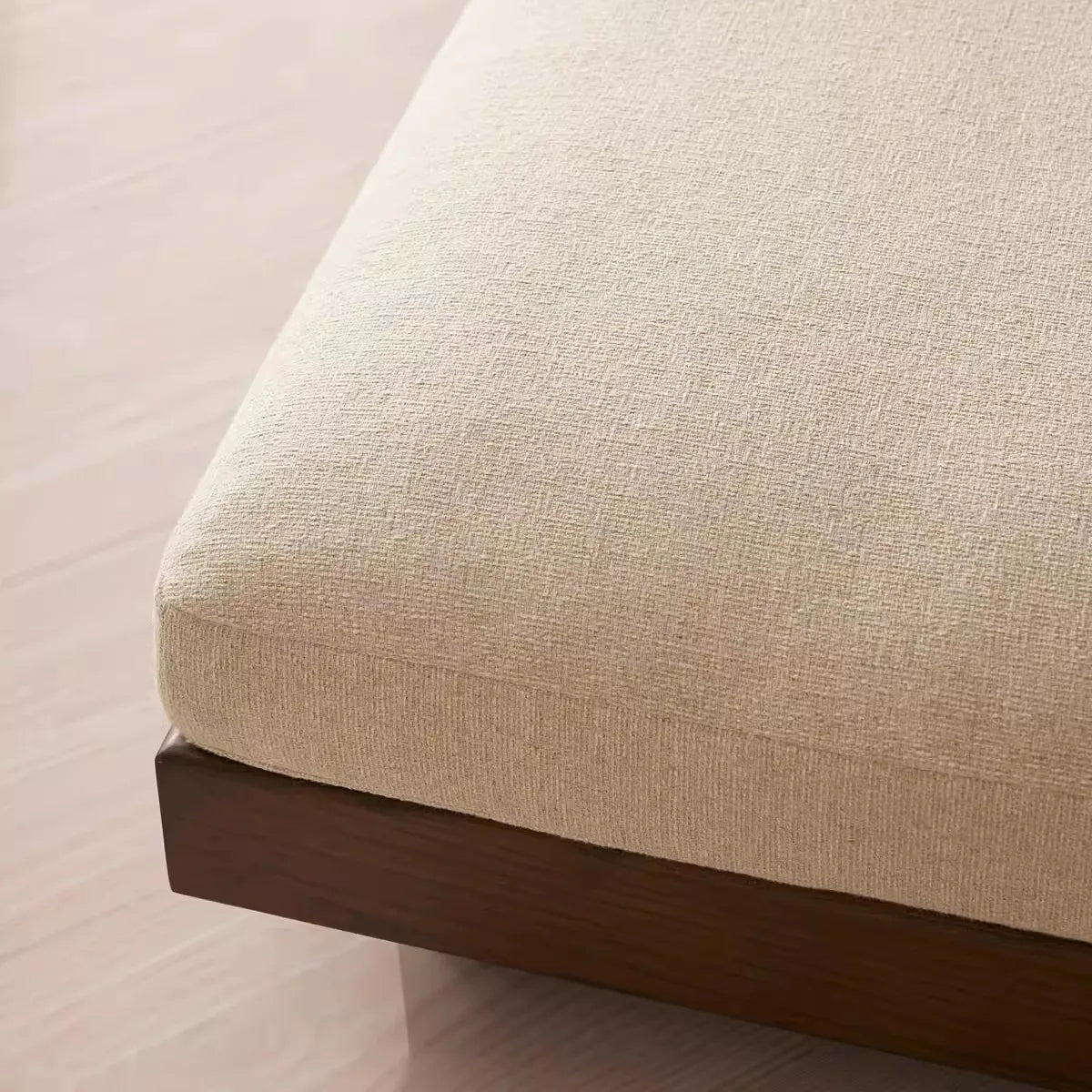 Close-up of a beige upholstered chair with a wooden base on a light background