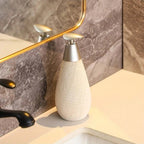 White textured soap dispenser on a bathroom counter with a mirror in the background.