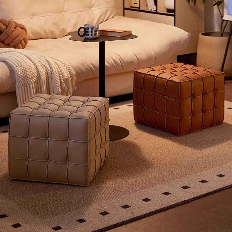 Two cube stools, one beige and one brown, in a living room setting.