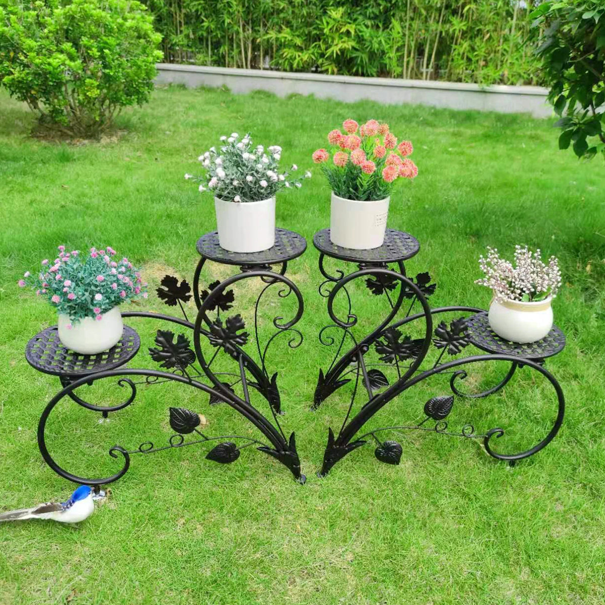 Decorative black metal plant stand with potted plants on a grassy lawn
