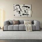 Gray sectional sofa in a living room with abstract art on the wall.