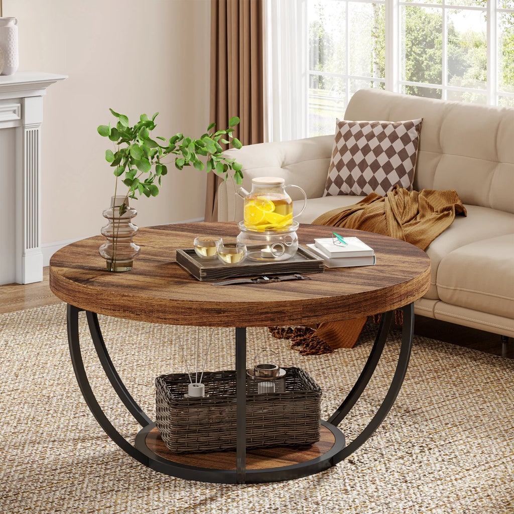 Round wooden coffee table in a living room with a teapot and books on top.