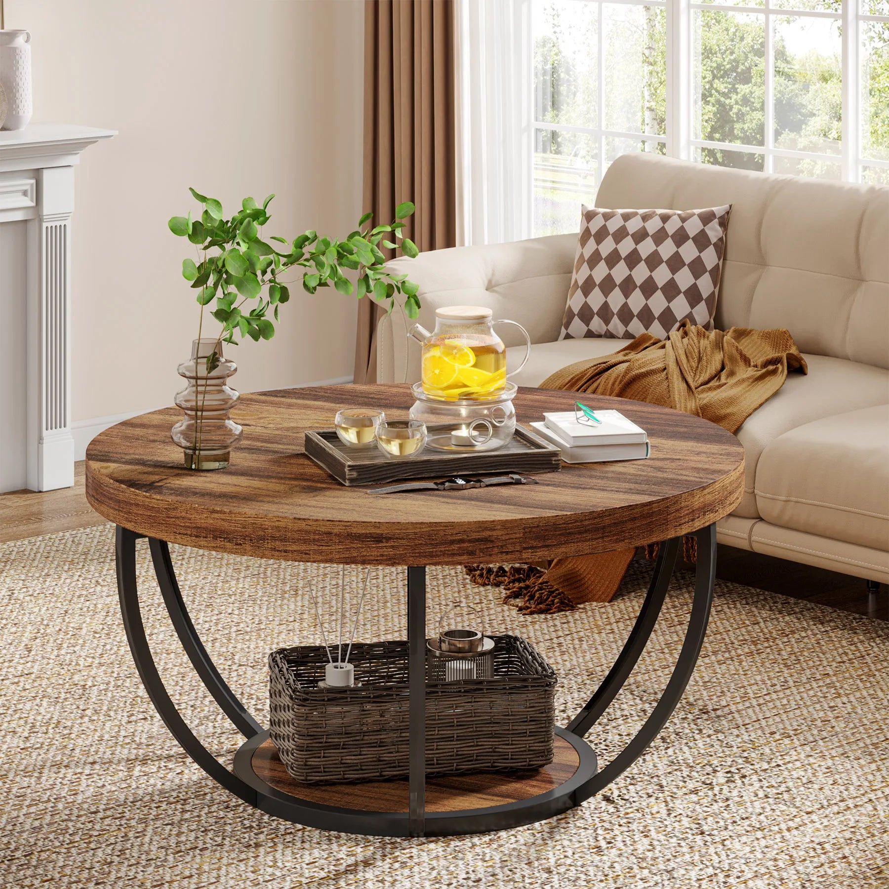 Round wooden coffee table in a living room with a teapot and books on top.