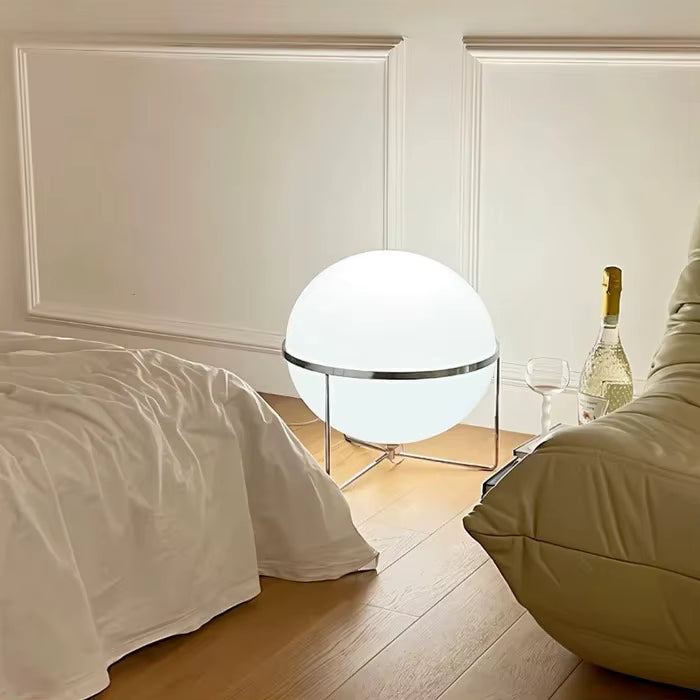 Modern bedroom with a round table lamp, bed, and sofa.