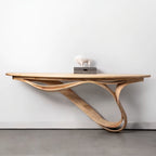 Wooden console table with wavy leg design against a white wall.