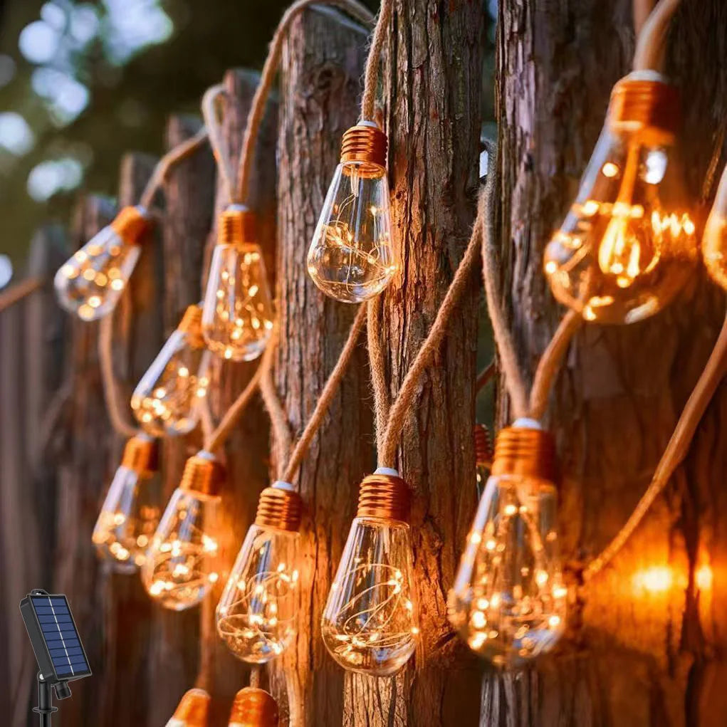 String of vintage-style light bulbs hanging on a wooden fence with a solar panel in the corner.