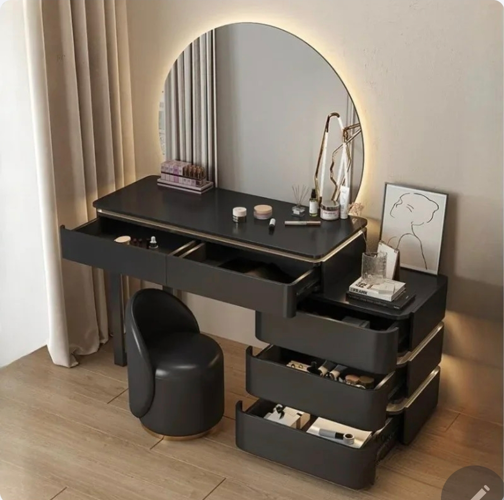 Black vanity table with round mirror and various items on a wooden floor.