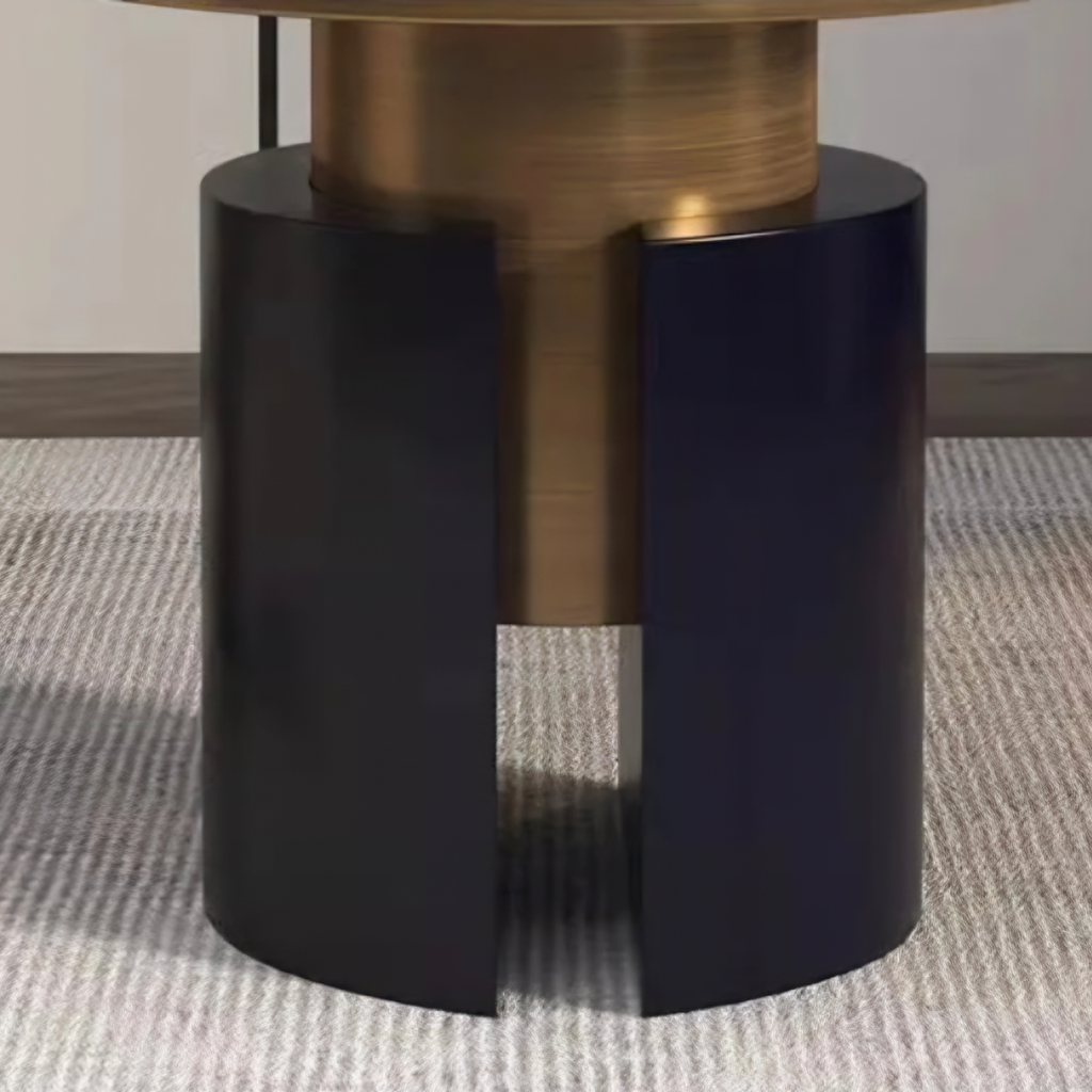 Close-up of a table base with a matte black split cylindrical pedestal and a brushed brass central column, shown on a textured light gray rug with overlaid text reading 'Stable chassis' and descriptive copy below.