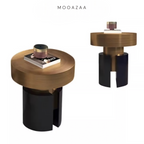 A modern round side table shown from two angles on a white background, with the brand name MOOAZAA at the top. The table features a brushed brass/gold top and a split black cylindrical base.