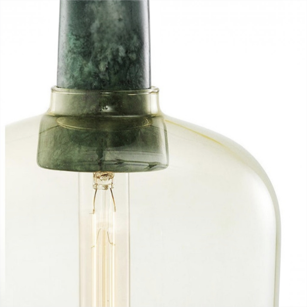 Close-up of a clear glass bottle or vase with a dark green marble-like neck and an exposed warm white filament bulb, on a white background.