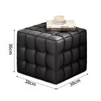 Black cube-shaped ottoman with dimensions and a book on top