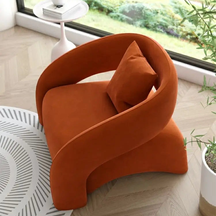Orange armchair with a pillow in a modern room with a window and plant.
