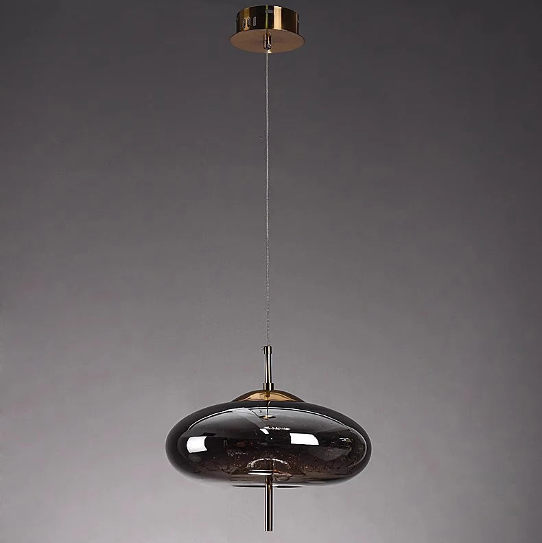 Modern pendant light with dark glass shade and gold accents on a gray background