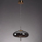 Modern pendant light with dark glass shade and gold accents on a gray background