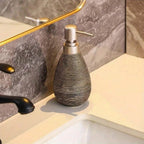 Decorative soap dispenser on a bathroom counter with marble wall and sink in the background