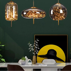 Three hanging glass pendant lights with decorative elements on a dark green wall.