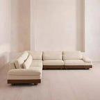 Beige sectional sofa in a minimalistic room with white walls and floor.
