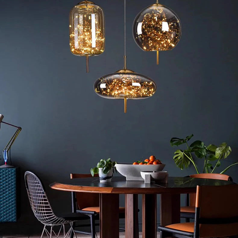 Dining area with a wooden table and chairs, illuminated by three hanging glass pendant lights against a dark wall.
