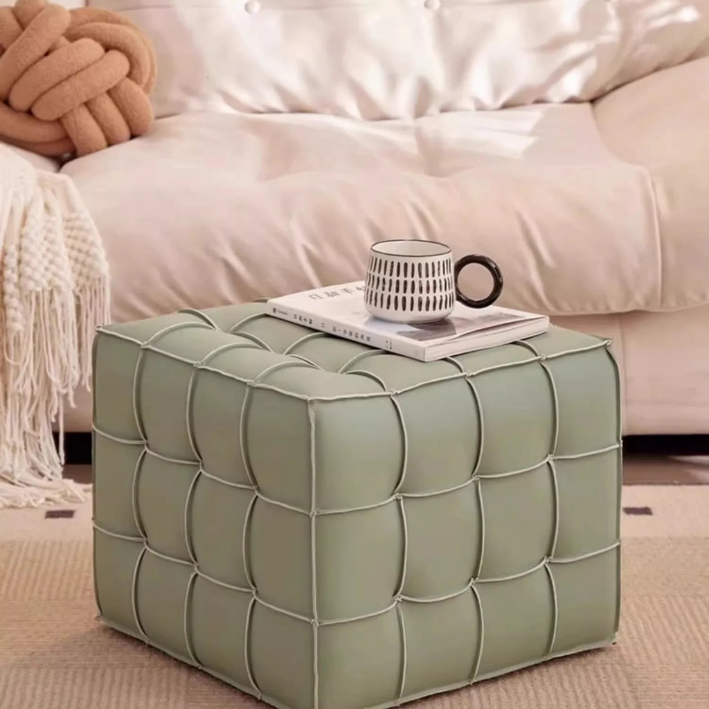 Green cube ottoman with a cup and book on top in a living room setting.