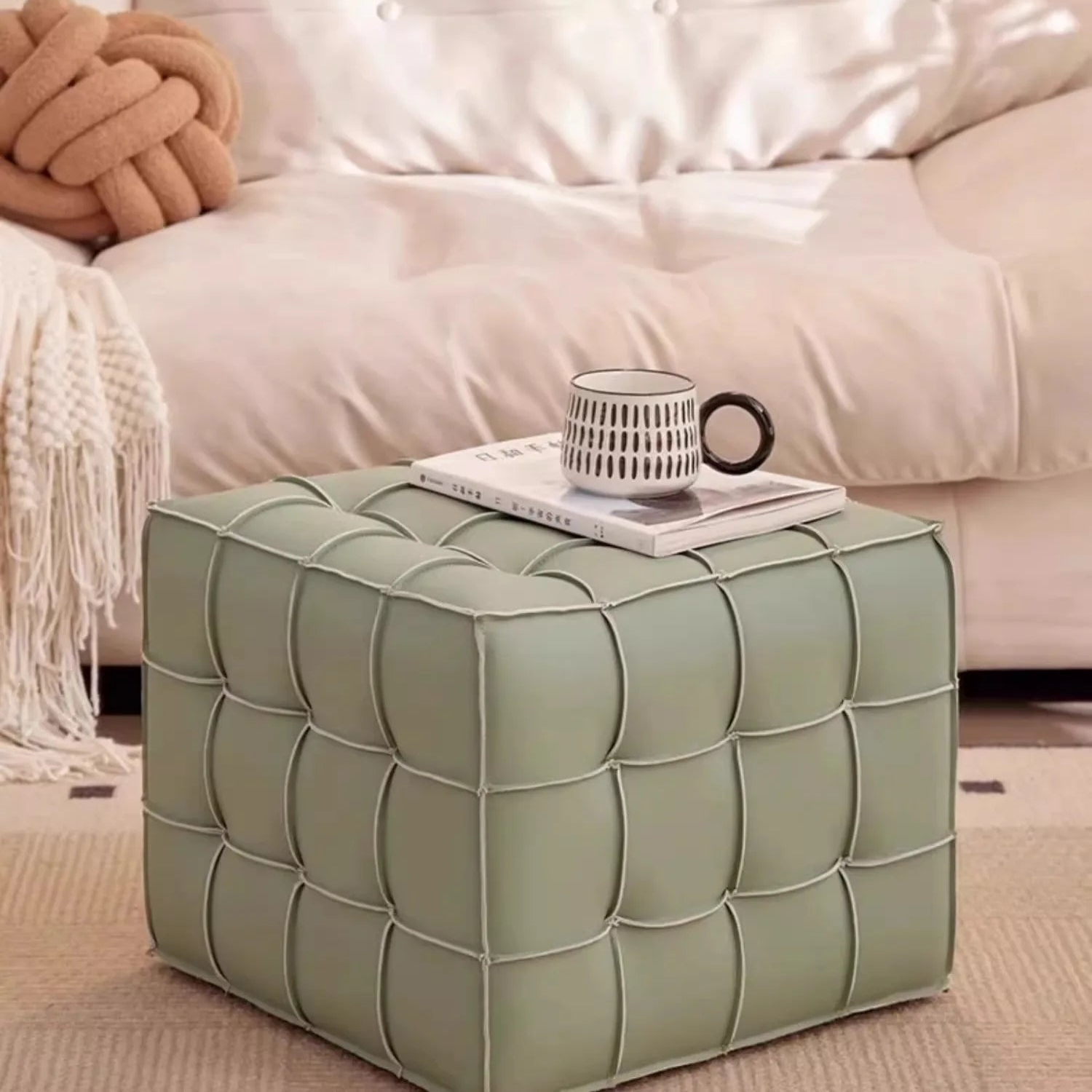 Green cube ottoman with a cup and book on top in a living room setting.