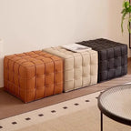 Three tufted ottomans in brown, beige, and black on a patterned rug.
