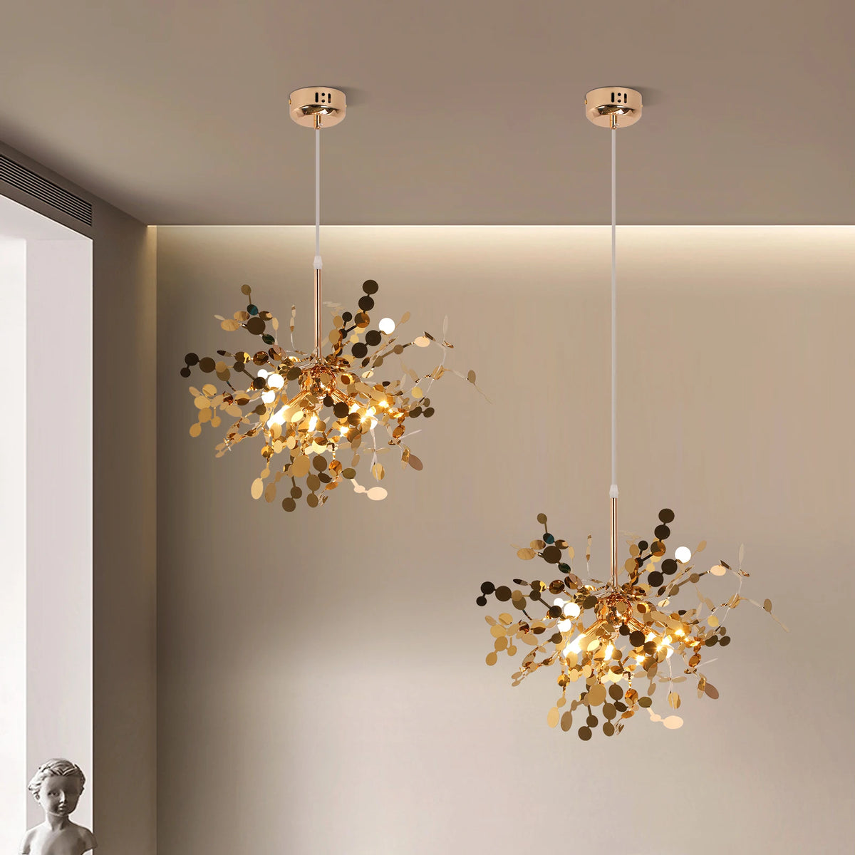 Two gold chandelier lights hanging in a room with neutral walls.