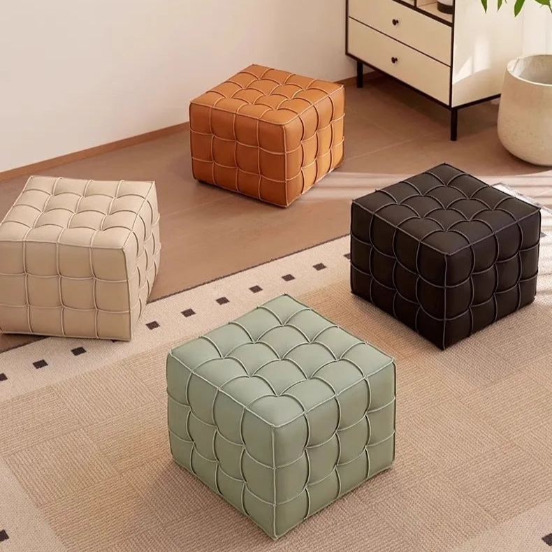 Four tufted ottomans in different colors on a patterned rug.