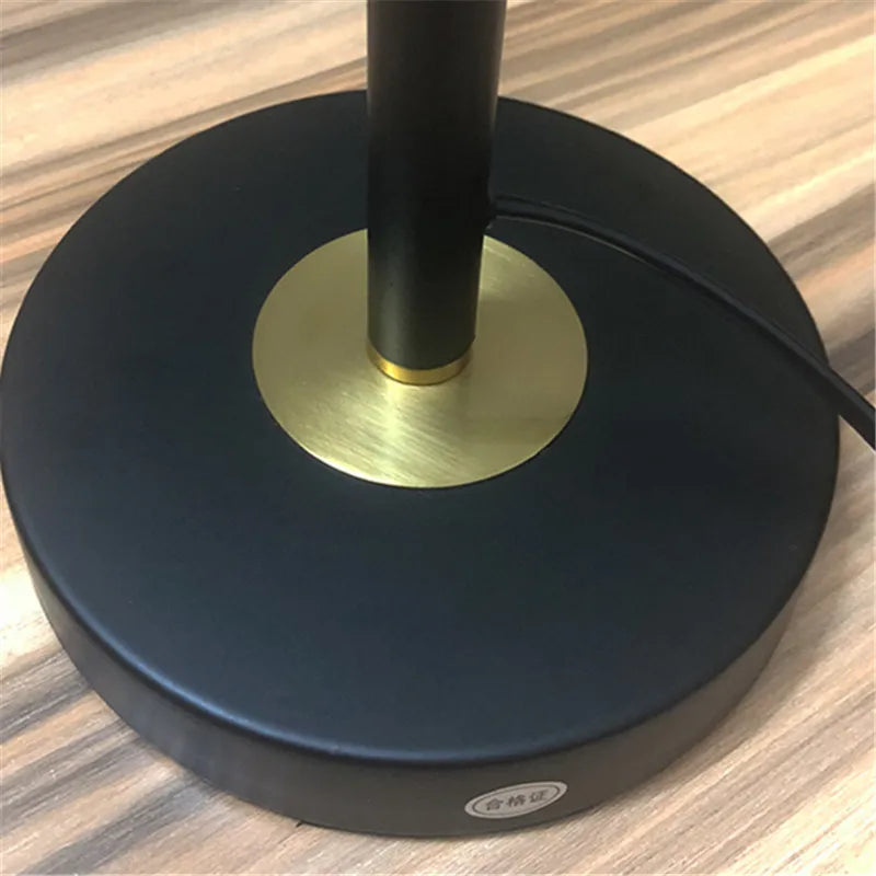 Close-up of a lamp base with black and gold design on a wooden surface