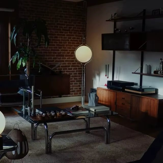 Darkly lit living room with a brick wall, wooden furniture, and decorative items.