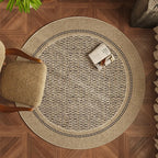 Round woven rug on a wooden floor with a chair and decorative items.
