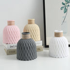 Four textured ceramic vases in pink, beige, gray, and white on a light surface.
