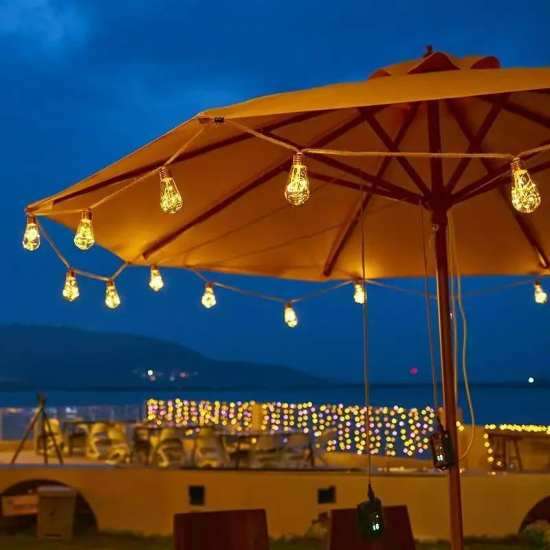 Large outdoor umbrella with string lights against a night sky.