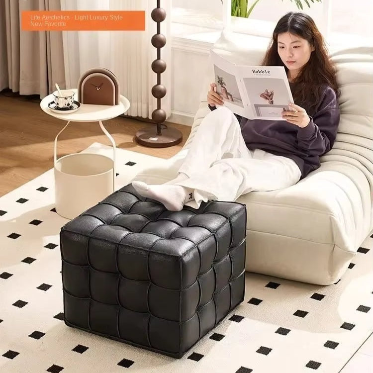 Woman reading a magazine on a white sofa with a black leather ottoman in front.