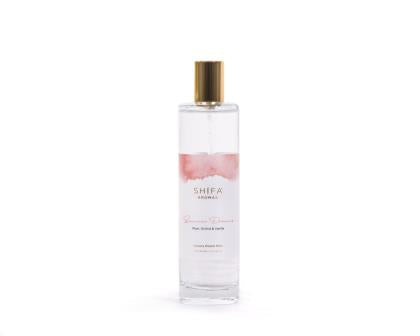 Perfume bottle with a gold cap and white label on a light pink background