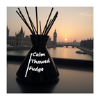 Black vase with 'Calm Thawed Fudge' text against a sunset cityscape background