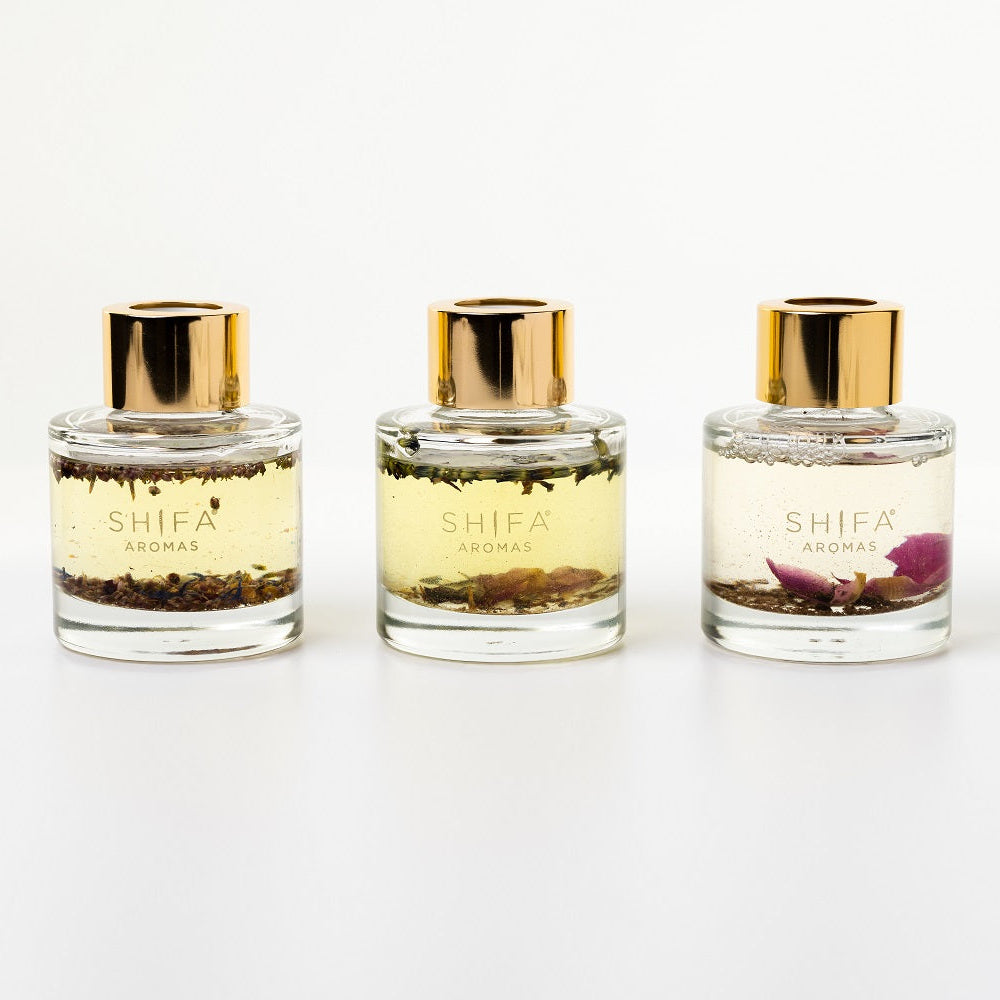 Three Shifa perfume bottles with gold caps on a white background