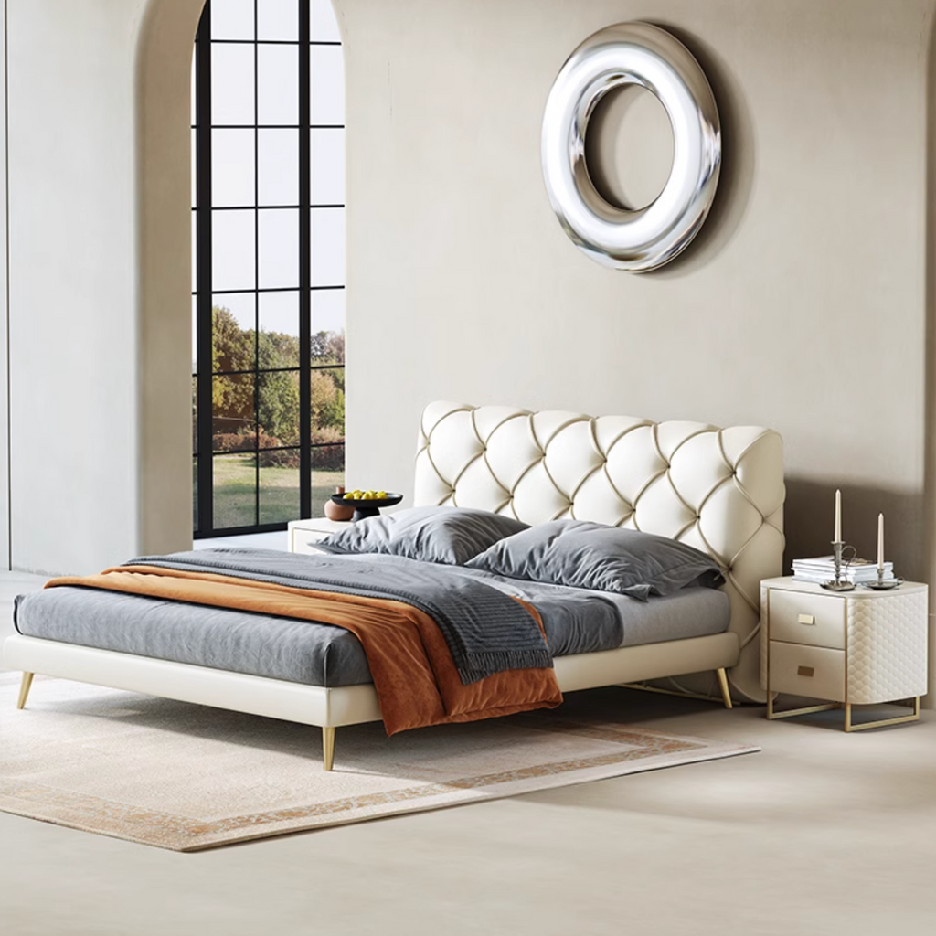 Modern bedroom with a tufted bed, nightstand, and decorative mirror.