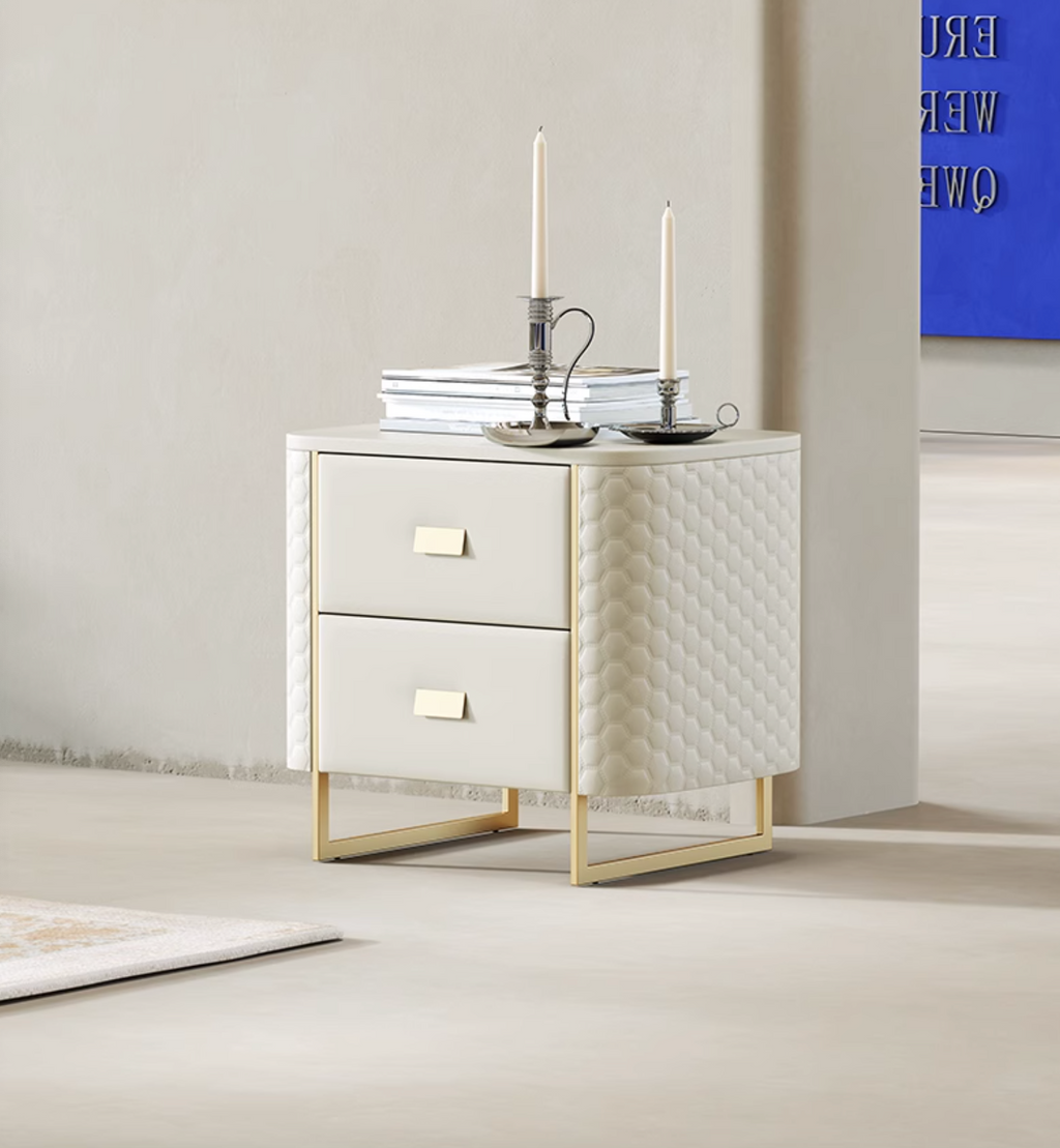 White nightstand with quilted design and gold accents in a room with a blue abstract painting.