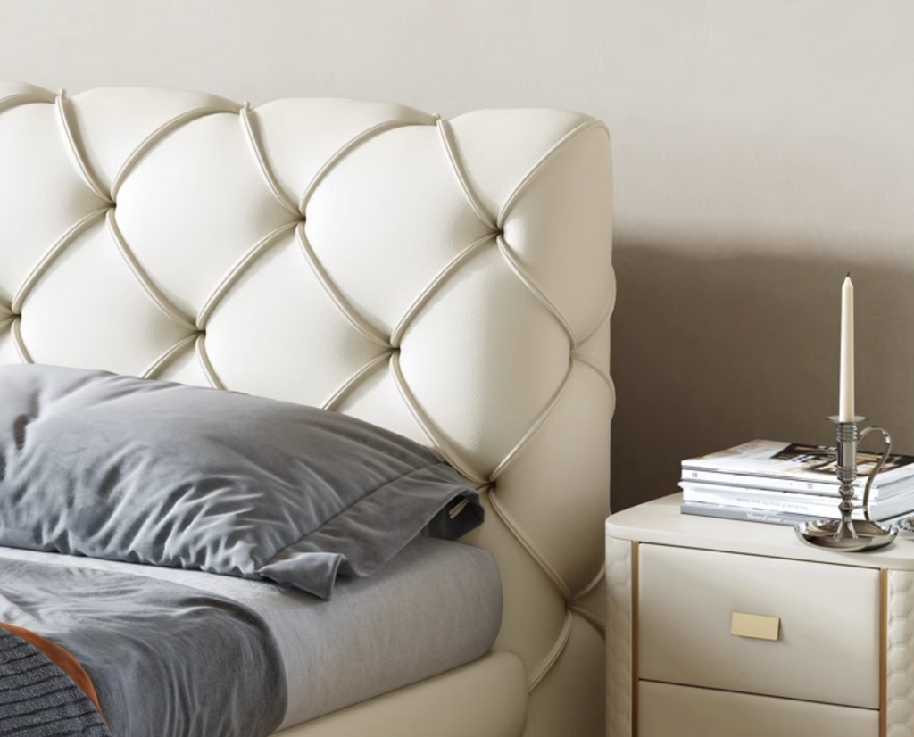 Beige tufted headboard with a nightstand and books in a bedroom setting