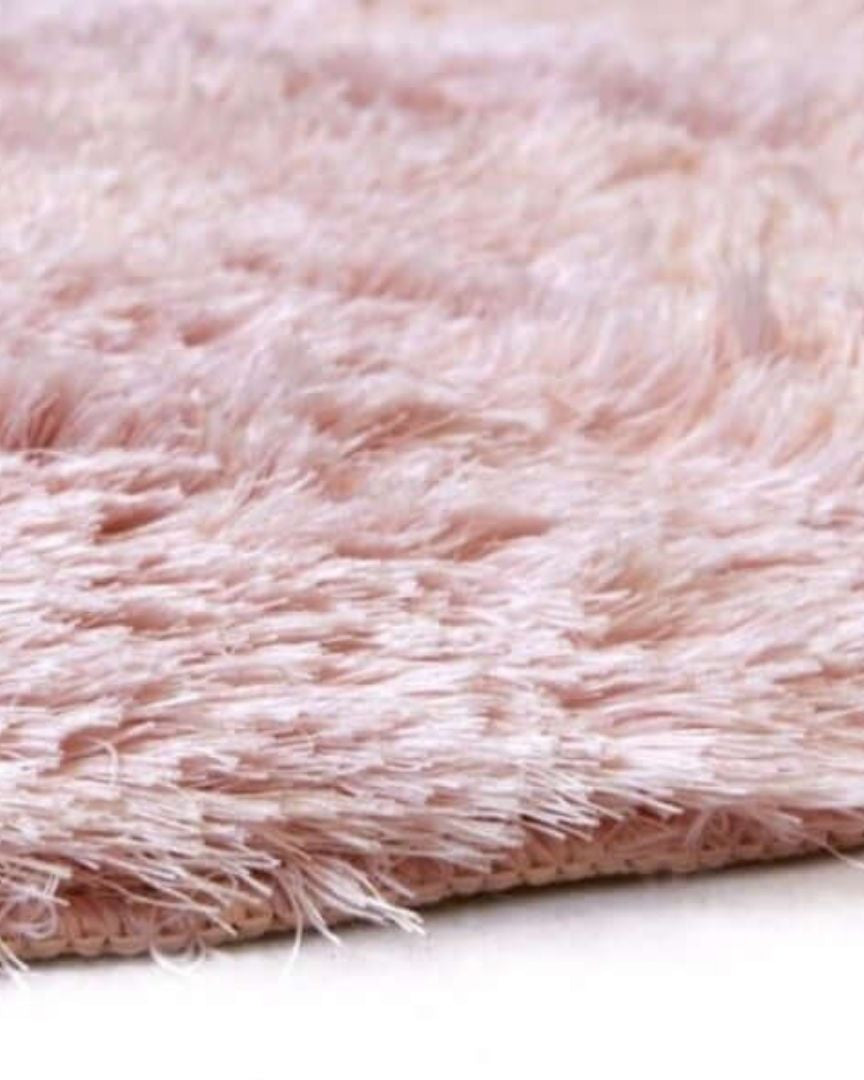 Close-up of a pink fluffy rug on a white surface