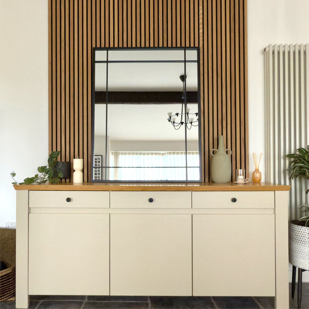 Beige sideboard with wooden top in a room with a mirror and decorative items.