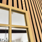 Close-up of a gold-framed window with wooden slats in the background