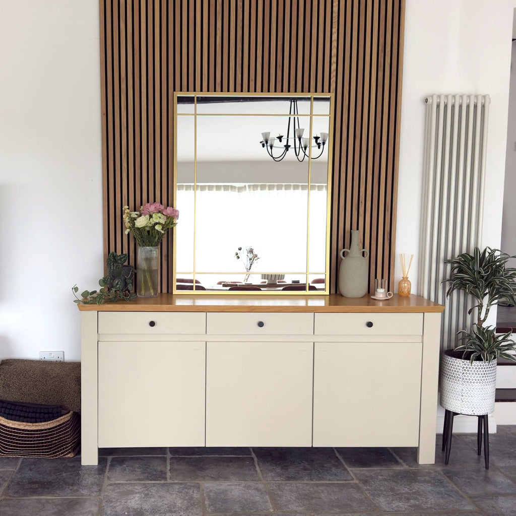 Beige sideboard with wooden top in a room with striped curtains and a mirror.