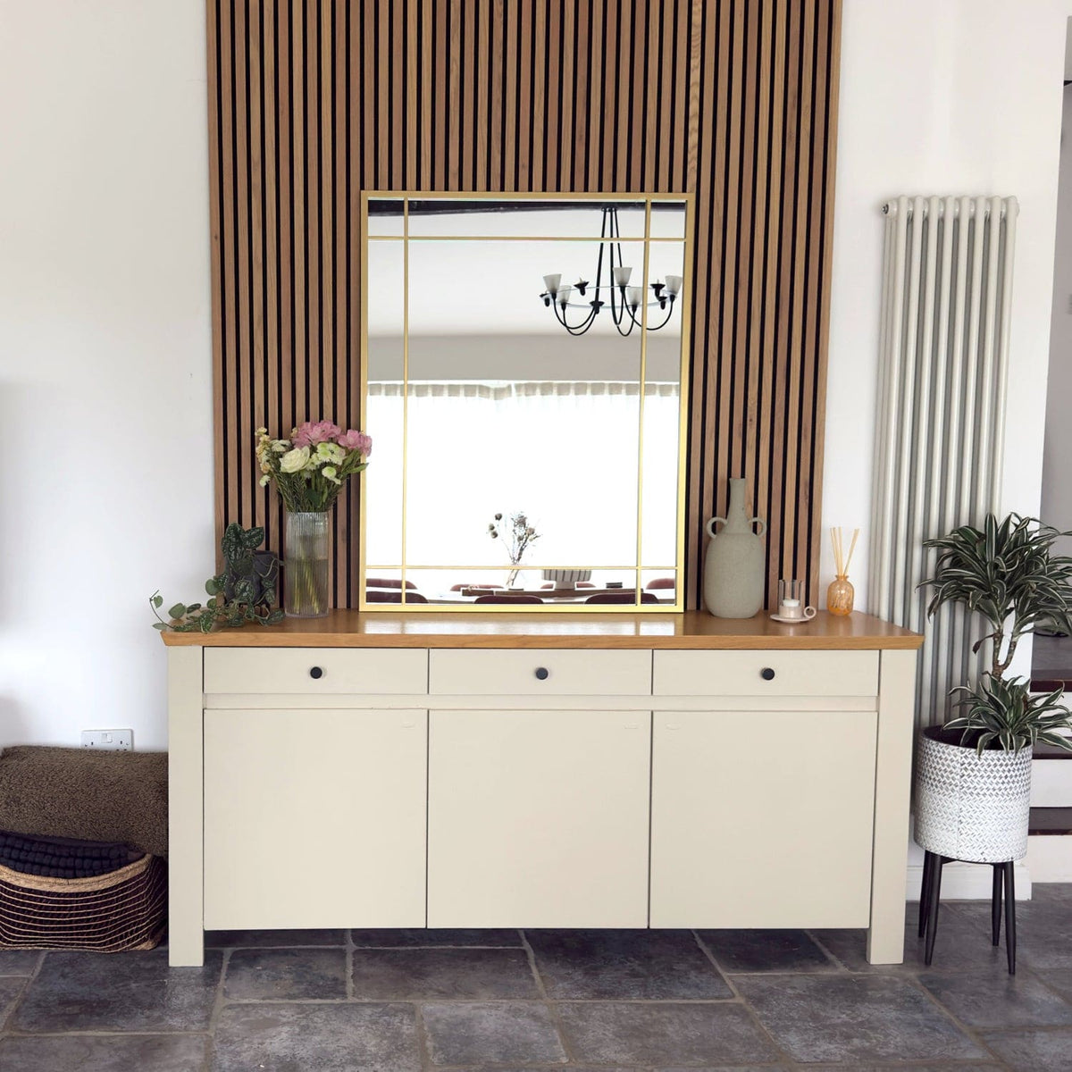 Beige sideboard with wooden top in a room with striped curtains and a mirror.